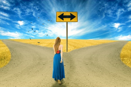 Young woman standing in front of two roads arrow sign